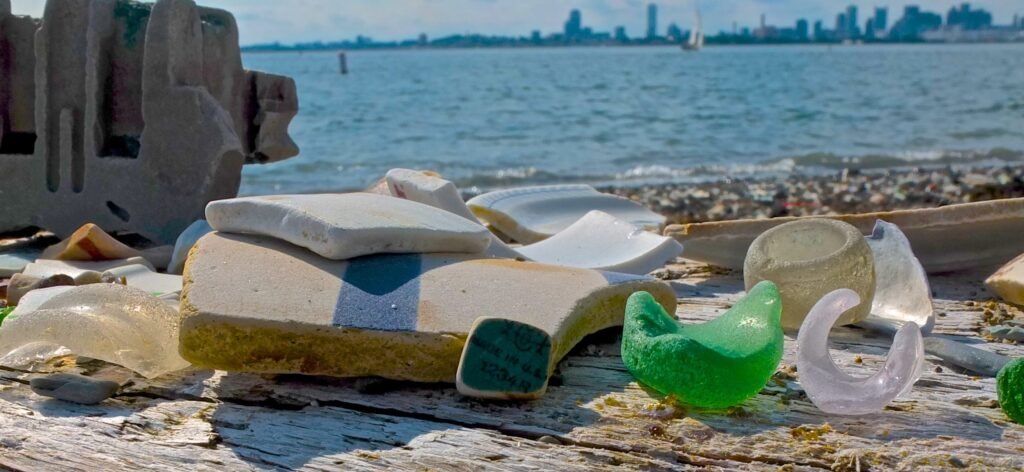 Photo of broken pottery and seaglass with Boston Skyline in background