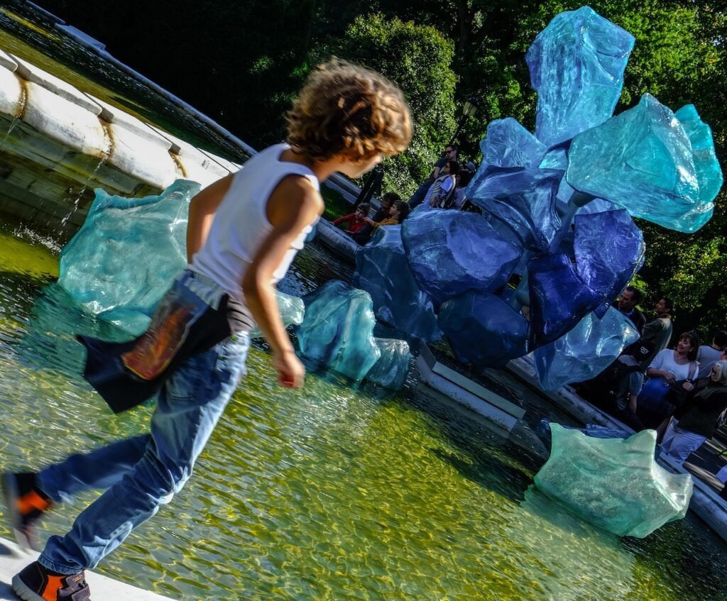 photograph of child running next to reflecting pond with Chiluly glass art installation